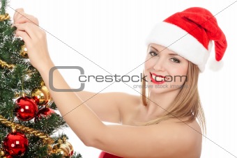 Pretty woman dressed as Santa Claus is standing beside a fir tre