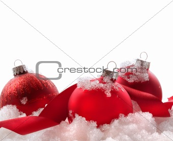 Red christmas balls and ribbon in snow on white