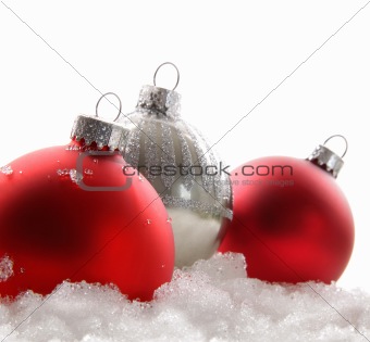 Three red christmas balls in the snow on white