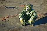 Scientist in protective suit and gas mask sitting on slag