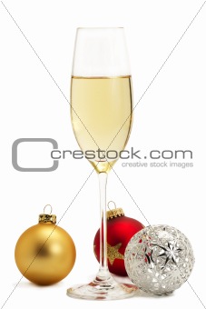 glass of champagne with golden, red and metal christmas balls