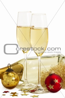 two glasses of champagne with angels hair, red and golden christmas balls in front of a champagne bottle
