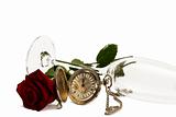 old pocket watch with a red wet rose under a lying champagne glass