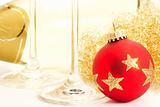 closeup of a red dull christmas ball with champagne glass bottom in front of a champagne bottle