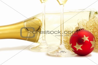 red christmas ball in front of angels hair, two champagne glasses bottoms and a champagne bottle