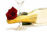 wet red rose on a champagne bottle behind a champagne glass