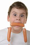 Surprised boy holds sausage in mouth
