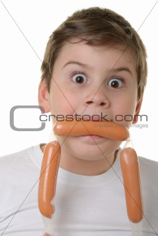 Surprised boy holds sausage in mouth