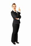 Full length portrait of interested modern business woman pointing finger up

