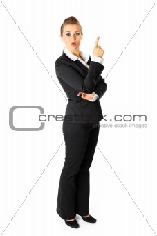 Full length portrait of interested modern business woman pointing finger up
