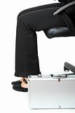 Suitcase at legs  of business woman sitting on chair

