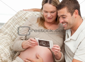 Lovely couple looking at an echography while relaxing