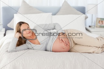 Pensive future mom lying on a bed