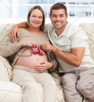 Lovely couple putting baby shoes on the woman's belly