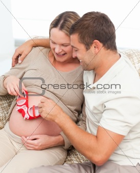 Cute man playing with baby shoes on his wife's