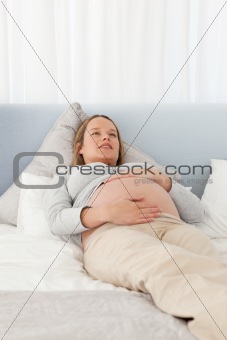 Pretty pregnant woman resting on a bed