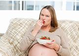 Young pregnant woman eating a strawberry