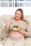 Beautiful pregnant woman holding a bowl of salad