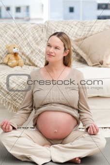 Pensive pregnant woman doing yoga sitting on the floor
