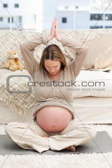 Pregnant woman doing yoga on the floor of her living-room 