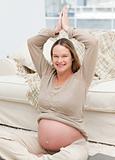 Charming pregnant woman doing yoga exercises on the floor