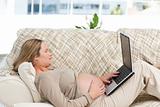Caucasian pregnant woman working on a laptop while relaxing