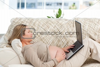 Caucasian pregnant woman working on a laptop while relaxing