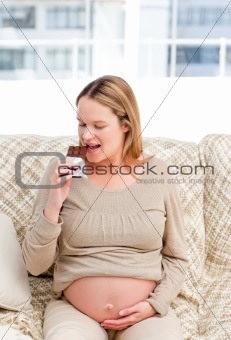 Joyful pregnant woman enjoing chocolate while resting