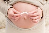 Close up of an attentive pregnant woman breaking a cigarette 