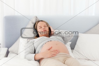 Relaxed future mom listening to the music on a bed 