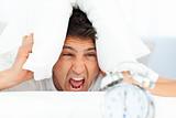 Angry man putting his head under the pillow