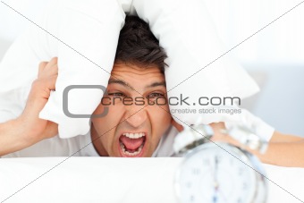 Angry man putting his head under the pillow
