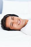 Cheerful man listening music with headphones lying on his bed