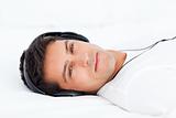 Charismatic man listening music lying on his bed 