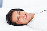 Portrait of a happy man listening music lying on his bed