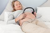 Happy future mom putting headphones on her belly