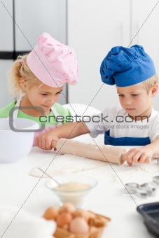 Little girl looking at her serious brother using a rolling pin