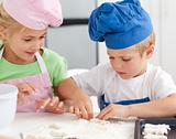 Young brother and sister kneading a dough to make cakes