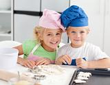 Portrait of two adorable children baking in the kitchen 