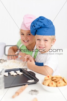 Adorable siblings kneading together a dough in the kitche