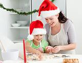 Adorable girl with her mother baking Christmas cookies