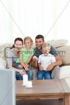 Happy family laughing while watching television sitting 