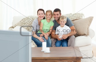 Adorable family watching television together sitting on the sofa