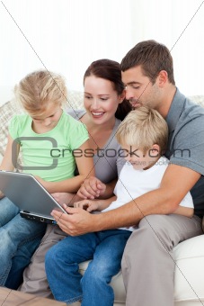 Parents and children using their laptop together sitting on the 