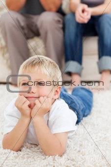 Cute little boy watching television lying on the floor