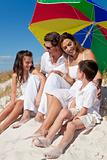 Family Laughing Under Colorful Umbrella On Beach