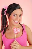 Beautiful happy teenage girl with a heart shaped lollipop . pink