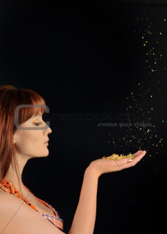 Young beautiful woman blowing golden stardust from her hand