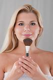 beautiful girl applying powder make-up with brush