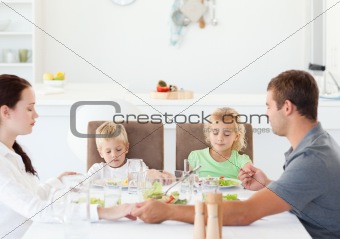 Family praying together before eating their salad for lunch